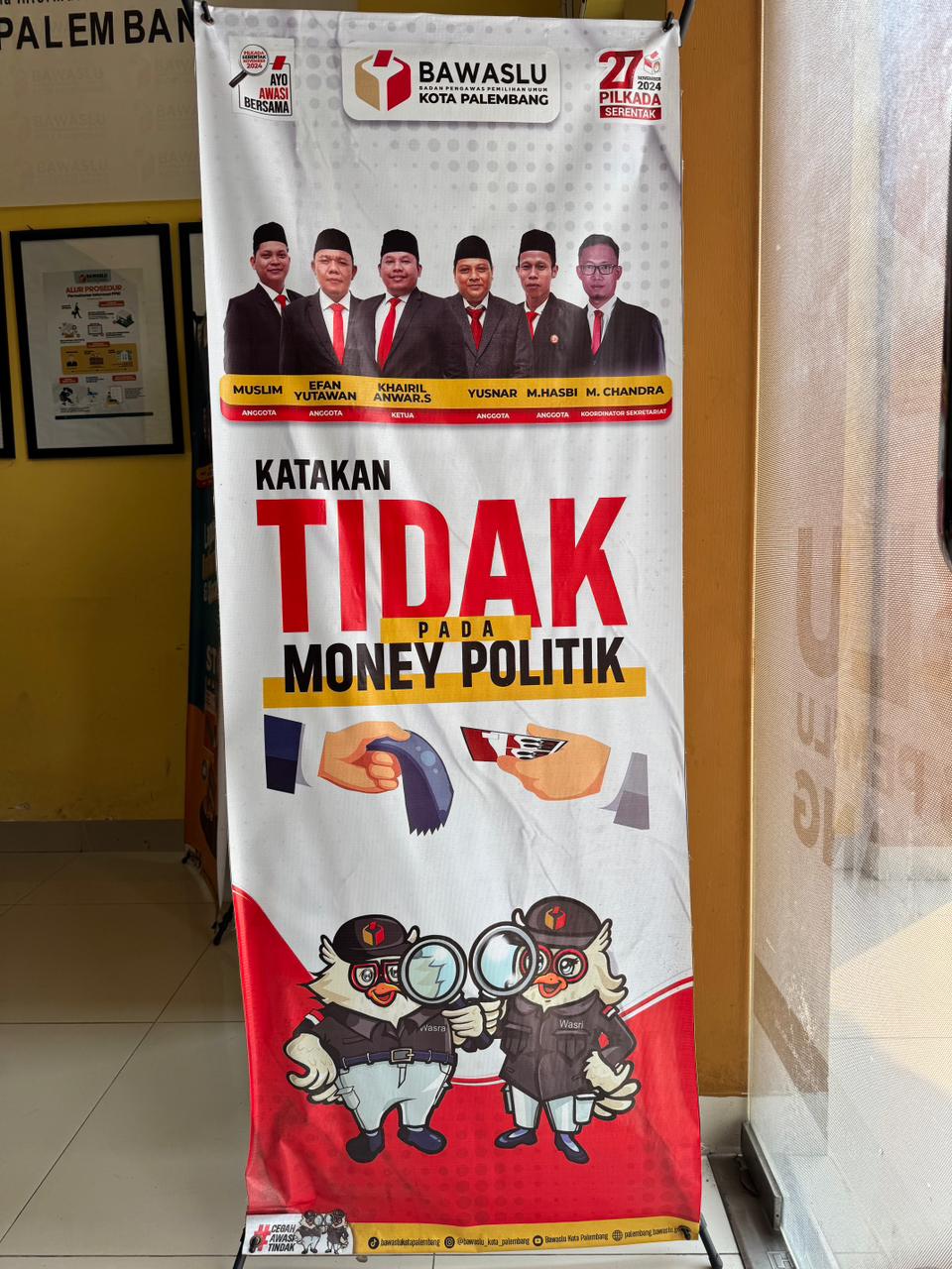 Spanduk kampanye “Katakan Tidak pada Money Politik” terpajang di area pelayanan publik Bawaslu Kota Palembang, menampilkan jajaran pimpinan lembaga (dari kiri ke kanan): Muslim, Efan Yutawan, Khairil Anwar Simatupang, Yusnar, M. Hasbi, dan M. Chandra, Selasa (4/11/2025). Foto: Tim Humas Bawaslu Kota Palembang